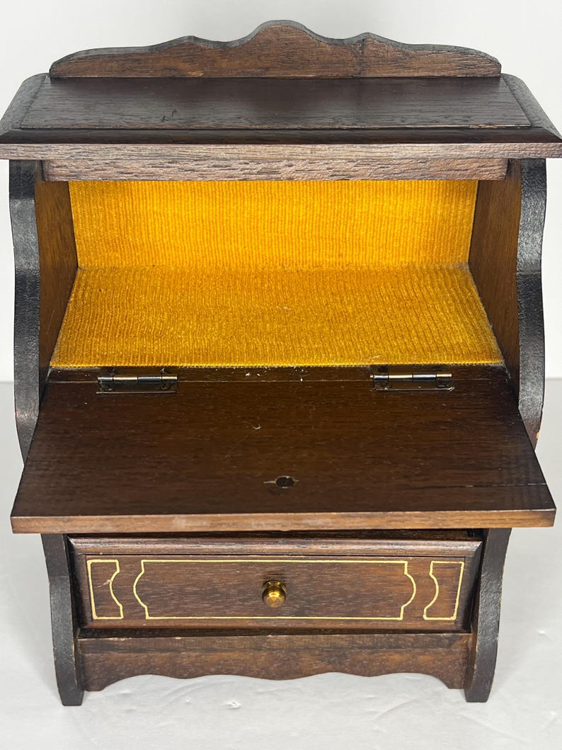 Puede incluir: Un peque&ntilde;o escritorio de madera con tapa abatible y un caj&oacute;n. El escritorio tiene un forro de terciopelo amarillo en el interior.