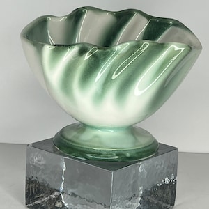 May include: A white ceramic bowl with green and white swirling glaze. The bowl is on a clear glass pedestal.
