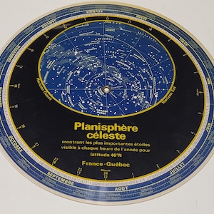 Könnte beinhalten: Ein kreisförmiges Planisphäre mit blauem und schwarzem Design, das eine Sternenkarte und Himmelsinformationen zeigt. Der Text "Planisphère céleste" ist sichtbar, zusammen mit anderem französischen Text. Das Planisphäre ist für den Breitengrad 46°N konzipiert.