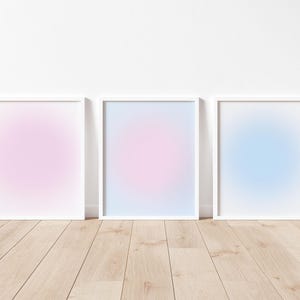 以下が含まれることがあります： 薄いピンク、薄い青、薄い紫のグラデーションの背景を持つ、白い絵の額縁が3つあります。