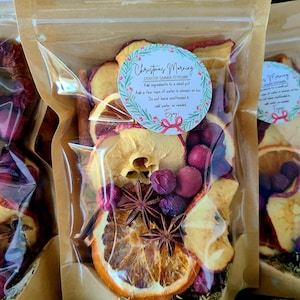 May include: Clear cellophane bags filled with dried fruit and spices. The bags contain orange slices, apple slices, cranberries, and star anise. A circular sticker on the bag reads "Christmas Morning" and provides instructions for use.