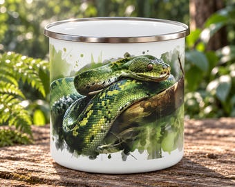 May include: A white enamel mug featuring a detailed graphic print of a green snake coiled around a brown tree branch. The mug has a smooth white interior and a metallic silver rim, showcasing a vibrant watercolour-style illustration of the reptile.