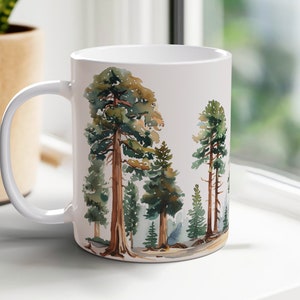 May include: White ceramic mug with a watercolor illustration of a forest scene featuring tall green trees with brown trunks.