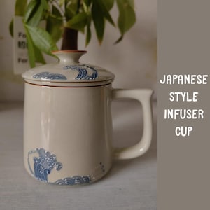 May include: Cream-coloured Japanese-style infuser cup with a lid and handle. The cup features blue wave designs and the text "JAPANESE STYLE INFUSER CUP". The cup is designed for steeping tea.