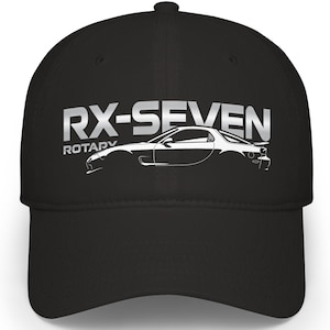 Puede incluir: Gorra de béisbol negra con el texto "RX-SEVEN ROTARY" en letras plateadas. Un contorno blanco de un coche deportivo aparece debajo del texto. La gorra tiene una visera curva y una corona estructurada.