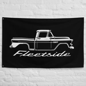 May include: Black flag featuring a white outline of a classic pickup truck. The truck's design includes a cab, bed, and fenders. The word "Fleetside" is written in a cursive font below the truck.