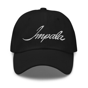 Könnte beinhalten: Schwarze Baseballkappe mit dem in weißer Schrift gestickten Wort "Impala" auf der Vorderseite. Die Kappe hat einen gebogenen Schirm und einen Knopf oben. Ein klassisches, lässiges Accessoire.