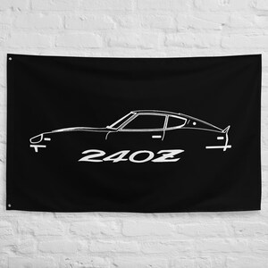 May include: Black flag featuring a white outline of a classic 240Z sports car. The car's silhouette is detailed, with the model name prominently displayed in white. The flag is rectangular and hangs against a white brick wall.