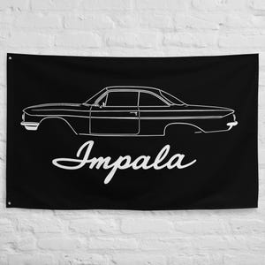 May include: Black flag with a white outline of a classic Impala car. The word "Impala" is written in a cursive font below the car illustration. The flag has eyelets in the corners for hanging.