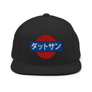 May include: Black baseball cap with a flat peak. The cap has a red circle with a blue rectangle bearing white Japanese text. A classic style, the cap is suitable for casual wear.