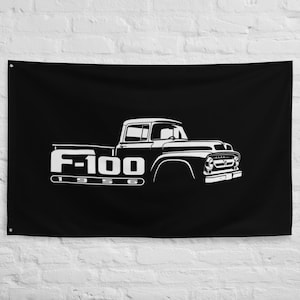 May include: Black wall flag featuring a white graphic of a vintage F-100 pickup truck. The truck's silhouette is detailed, with the text "F-100 1956" in a bold, stylized font. The flag has grommets for hanging.