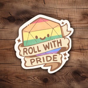 May include: A sticker featuring a rainbow-colored D20 die with a smiling face. A banner below reads "ROLL WITH PRIDE" in brown text. The sticker has a white border and is set against a wooden background.