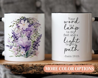 May include: White ceramic mug with a black rim and handle. The mug features a floral design with purple and white flowers and a quote: "Your word is a lamp to my feet and a light to my path -Psalm 119:105".