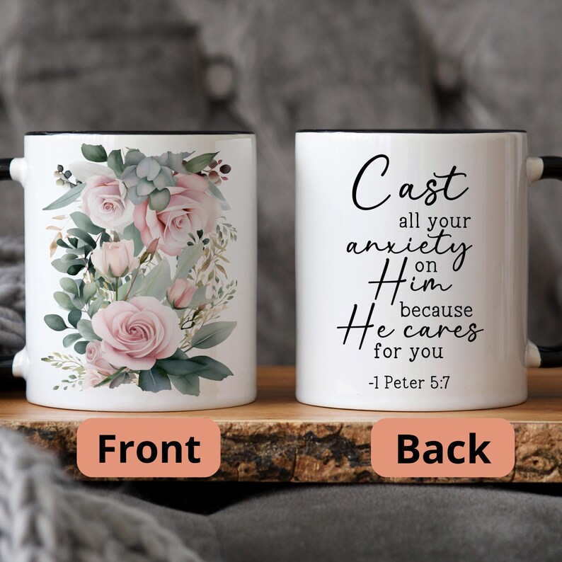 May include: White ceramic mug with a black rim and handle. The front features a floral design with pink roses and green leaves. The back features the text "Cast all your anxiety on Him because He cares for you -1 Peter 5:7".