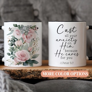 White ceramic mug with soft pink floral design and black 1 Peter 5:7 Bible verse text, perfect Christian gift for women