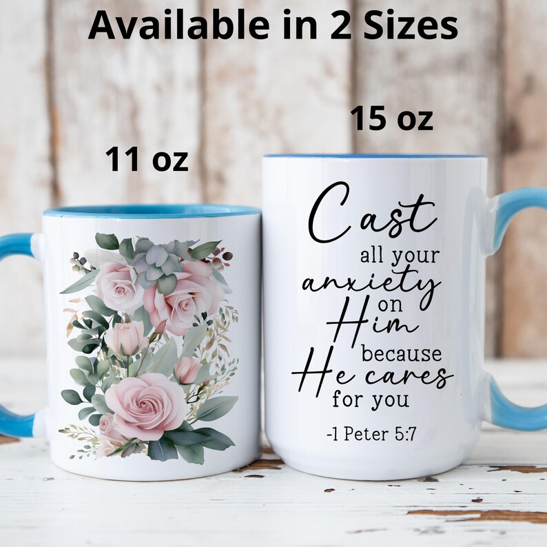 May include: White ceramic mug with a blue rim featuring a floral design with pink roses and green leaves. The mug has the text "Cast all your anxiety on Him because He cares for you -1 Peter 5:7" printed in black.