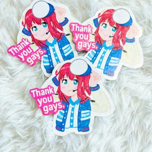 May include: Three stickers featuring an anime-style character with red hair, blue eyes, and a headset. The character wears a blue and white jacket with the text "Popurs". Each sticker has a pink speech bubble that says "Thank you gays."