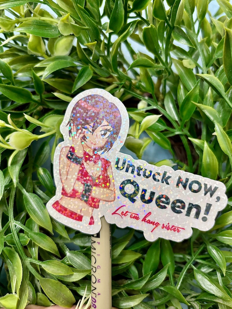 Puede incluir: Una pegatina hologr&aacute;fica con un personaje de estilo anime con un atuendo rojo. La pegatina tiene el texto "Untuck NOW, Queen! Let em hang sister" en una fuente divertida. La pegatina est&aacute; colocada frente a un fondo de hojas verdes.