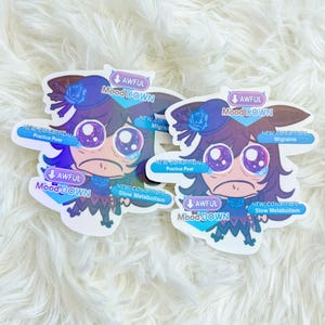 May include: Two stickers with a cartoon character with a downcast expression. The stickers have text that reads "AWFUL Mood DOWN" and "NEW CONDITION" with additional text indicating health issues. The stickers are on a white, fluffy surface.