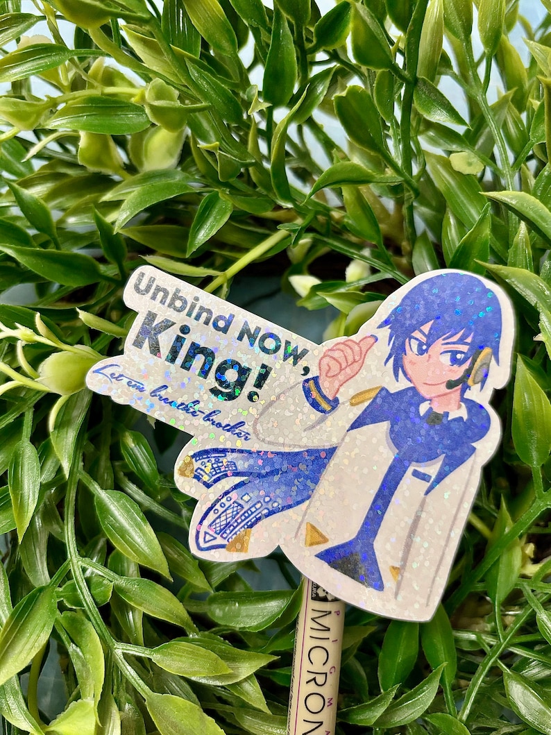 Puede incluir: Una pegatina brillante con un personaje de estilo anime en azul y blanco con el texto "Unbind NOW, King!" y "Let em breathe brother." La pegatina est&aacute; sobre un fondo de follaje verde.