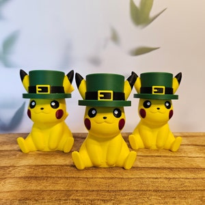 May include: Three yellow Pikachu figurines wearing green and black leprechaun hats. The hats have a gold buckle and a green band.