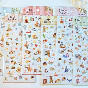 May include: A collection of six sticker sheets featuring the text "Little Kitchen" and various illustrations of animals cooking and baking. The stickers include images of food, kitchen utensils, and animals like foxes, rabbits, and bears. The sheets have different color schemes.