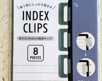 May include: A package of eight silver index clips for organizing notebooks. The package features Japanese text that reads "Index Clips" and "8 Pieces". The text on the package also reads "Organize your notebooks neatly. The index clips fit perfectly inside the cover."