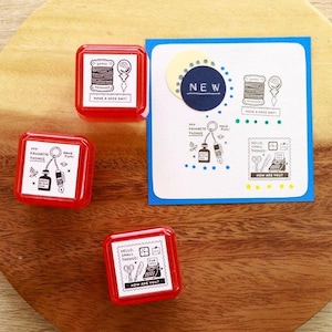May include: A collection of red square stamps with white ink designs and text, including phrases like "Have a Nice Day" and "How Are You?" A blue and white card with similar designs and the word "NEW" is also present.