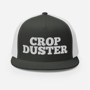 May include: A black and white trucker hat with a white mesh back. The front of the hat has the text "Crop Duster" in white.