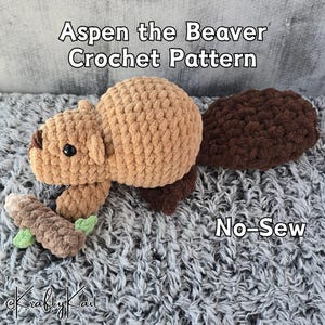 Peut inclure: Un jouet de castor crocheté en beige et marron, avec une queue marron foncé et une petite bûche avec des détails verts. Le texte indique "Aspen the Beaver Crochet Pattern" et "No-Sew".