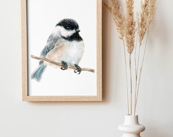 May include: A framed watercolor painting of a black-capped chickadee perched on a branch. The bird is depicted in a realistic style with delicate brushstrokes and soft colors.