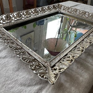 Peut inclure: Un plateau argenté avec une surface miroir et une bordure ornée, décorative en forme de feuille.