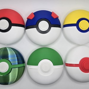 May include: Six spherical objects, reminiscent of Poké Balls, in various colours. Each has a white base and a coloured top: red, blue, yellow, green, and a green-blue gradient. A black or green band and a central white button complete the design.