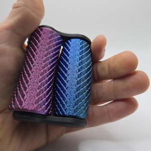 May include: Two textured grip covers, one in a deep purple and the other in a blue with green highlights. The covers are made of a textured material and have a black base.