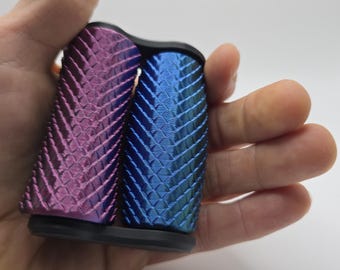 May include: Two textured grip covers, one in a deep purple and the other in a blue with green highlights. The covers are made of a textured material and have a black base.