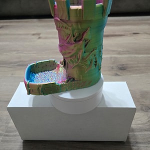 Könnte beinhalten: Ein regenbogenfarbener, 3D-gedruckter Würfelturm in Form eines Schlosses mit einem Drachen-Design. Der Turm steht auf einer weißen Basis und befindet sich auf einer weißen Box.