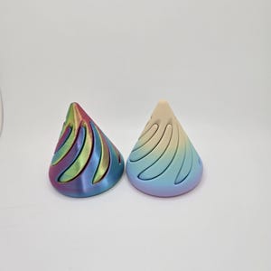 May include: Two colorful, 3D printed, cone-shaped objects with a swirling pattern. The cone on the left is pink, green, and blue. The cone on the right is yellow, blue, and pink.