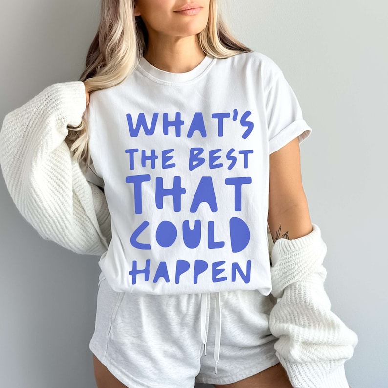May include: White t-shirt with the text "What's the best that could happen" in blue lettering.