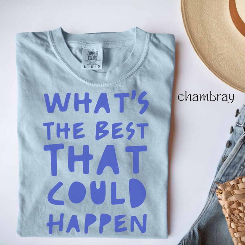 May include: A light blue t-shirt with the text "What's the best that could happen" printed in blue on the front. The shirt is made of a soft, comfortable fabric and is ideal for everyday wear.