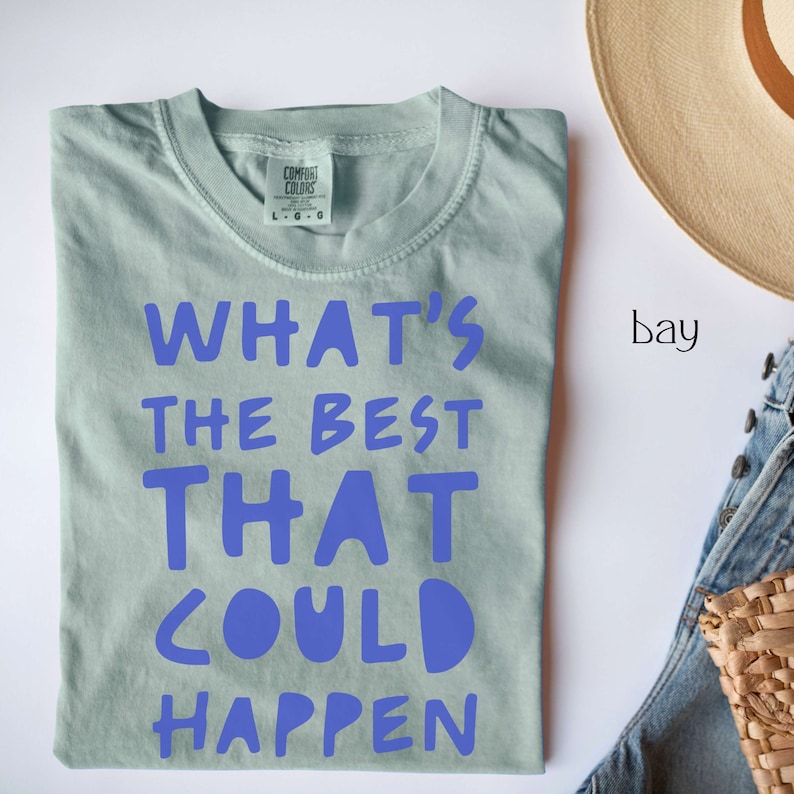 May include: A light blue t-shirt with the text "What's the best that could happen" printed in blue.