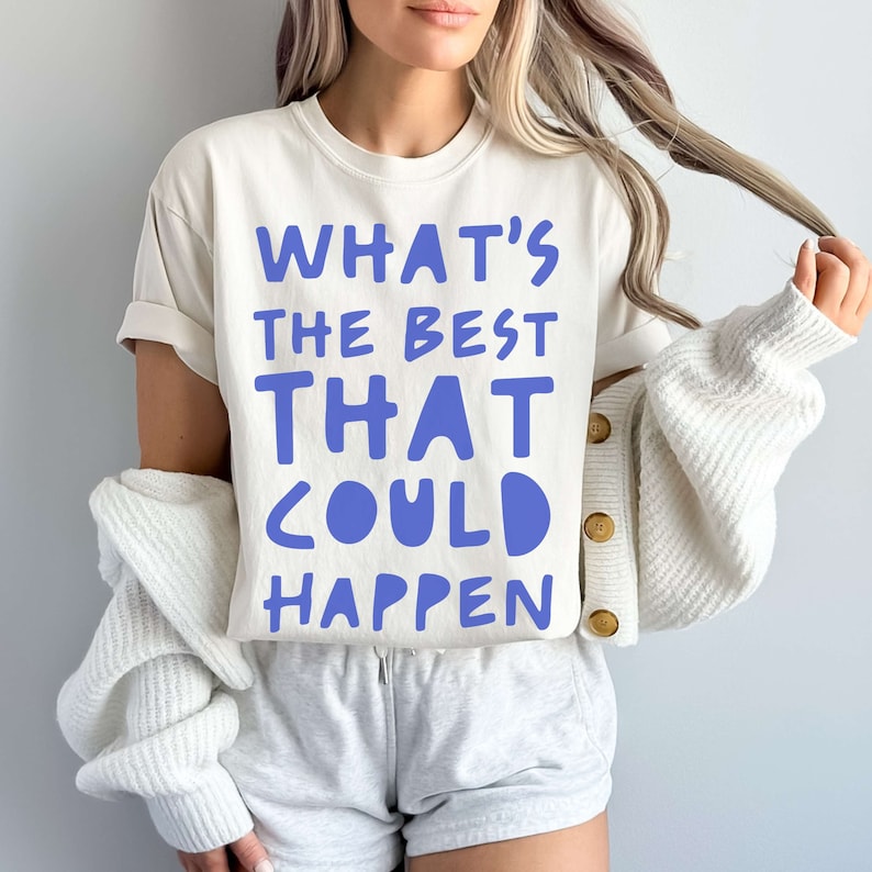 May include: A white t-shirt with the text "WHAT'S THE BEST THAT COULD HAPPEN" printed in blue.