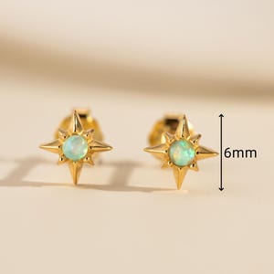 Puede incluir: Un par de pendientes dorados. Cada pendiente presenta un diseño de estrella con una piedra preciosa central, redonda y verde claro. Los pendientes miden aproximadamente 6 mm.