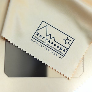 Puede incluir: Un paño de microfibra beige con un logotipo que dice "TerraScape" y "Protecting your Landscape Filters Gear!" con una dirección de sitio web debajo del logotipo: "www.terrascape.pt".