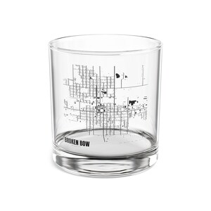 Könnte beinhalten: Ein klares Glas mit einem schwarz-weißen Kartendesign. Der Text "BROKEN BOW" ist auf der Unterseite des Glases aufgedruckt. Das Glas ist zylindrisch mit einem dicken Boden.