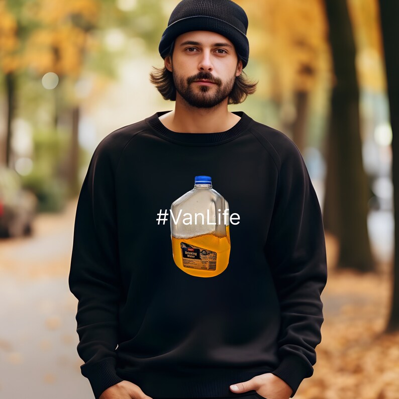 May include: A black sweatshirt with a graphic of a clear plastic jug of orange juice and the text "#VanLife" printed on the front.