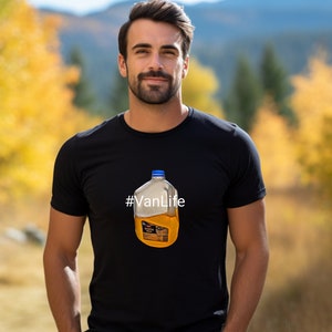 May include: A man wearing a black t-shirt with a graphic of a clear plastic jug filled with orange liquid. The text '#VanLife' is printed on the t-shirt.