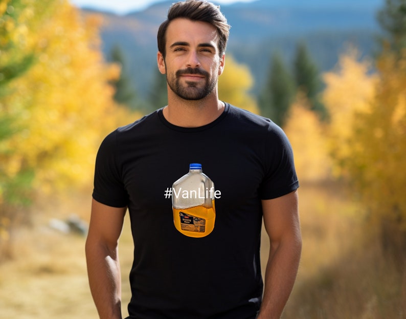 May include: A man wearing a black t-shirt with a graphic of a clear plastic jug filled with orange liquid. The text '#VanLife' is printed on the t-shirt.