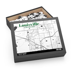 May include: A black and white jigsaw puzzle of a map of Louisville, Colorado. The puzzle is in a black box with the words "Louisville, Colorado" and "11x14 Puzzle, 252 pcs, Ages 9+" printed on it.