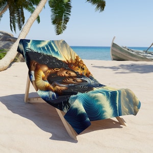 Może przedstawiać: Leżak plażowy z kolorowym ręcznikiem plażowym przedstawiającym dwie kobiety o ciemnej karnacji, które się obejmują. Ręcznik ma niebieski i złoty wzór z falami i koroną.