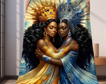 May include: Two women with dark skin and long black hair are embracing. They are wearing elaborate gold and blue crowns and matching gowns. The woman on the left is wearing a gold gown with intricate details and the woman on the right is wearing a blue gown with intricate details.